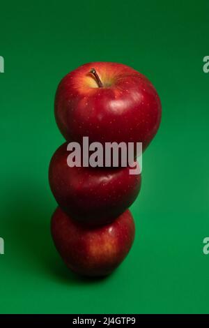 Three red delicious apples on green background Stock Photo