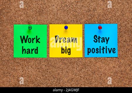 Three colored notes on corkboard with words Work hard, Dream big, Stay positive. Close-up Stock Photo