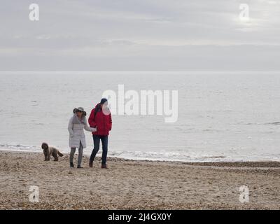 Couple walking along the beach in March, Highcliffe, Dorset, UK Stock Photo