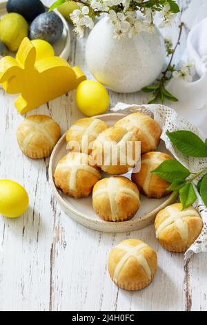 Happy Easter festive food concept. Homemade Easter traditional hot cross buns with raisin and natural colorful easter eggs on a rustic table. Copy spa Stock Photo