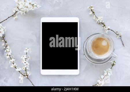Digital tablet mock-up and spring white cherry blossom flowers and morning coffee cup. Online shopping, studying, sales mockup. Spring flat lay, top view, copy space. Internet application template Stock Photo