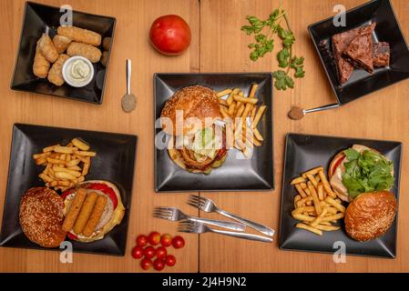 Set of fast food dishes and assorted beef burgers, meatballs with cream cheese, tequeños, chicken fingers, brownie pie Stock Photo