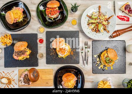 Set of fast food dishes and assorted burgers, salad with eggs, avocado and chicken, cakes and desserts Stock Photo