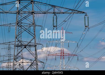 Metal pylons carrying overhead electric cables of high voltage lines. Concepts of electric transmission grids, energy supply, power consumption issues Stock Photo