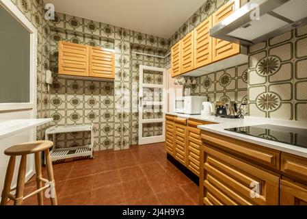 Kitchen with white stone countertops, solid wood cabinets, and vintage tile  on the walls Stock Photo - Alamy