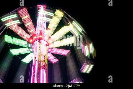 Multicolored Star Flyer tall Carousel rotating on long chains in an amusement park. Entertainment and leisure activities concept. Stock Photo