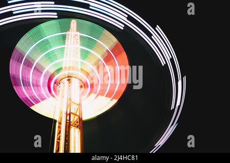 Multicolored Star Flyer tall Carousel rotating on long chains in an amusement park. Entertainment and leisure activities concept. Stock Photo