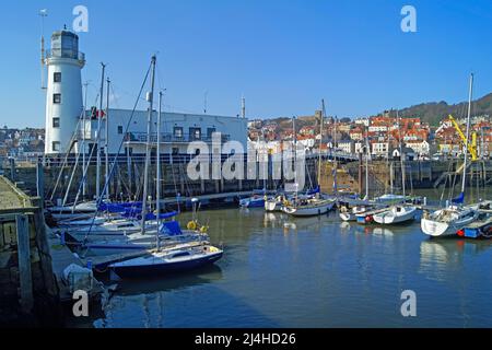 UK, North Yorkshire, Scarborough Lighthouse and Boats in Outer Harbour Stock Photo