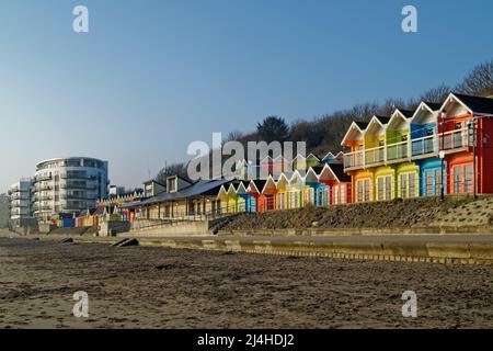 UK, North Yorkshire, Scarborough, Colourful Beach Chalets and The Sands Holiday Apartment Building on North Bay Promenade. Stock Photo