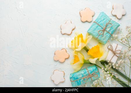 Yellow daffodils with gifts and biscuits on a wooden background, top view, with empty space for writing or advertising Stock Photo