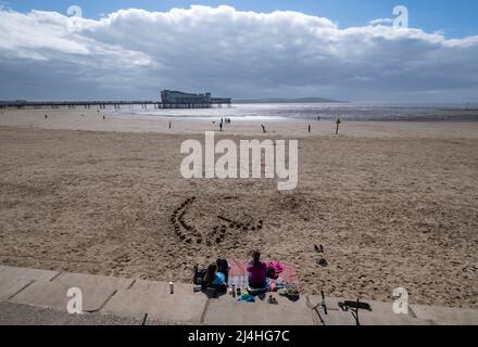 Holiday makers enjoy the beach at Weston Super Mare with the Grand Pier in the Bristol Chanel, Somerset. Stock Photo