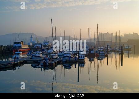 UK, North Yorkshire, Scarborough Harbour and Lighthouse looking towards West Pier with the Grand Hotel in the Distance. Stock Photo