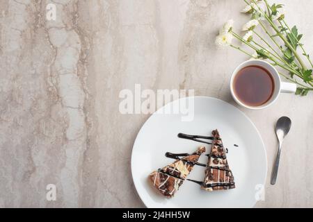 On the plate are two slices of cheesecake with tea and flowers, with space for congratulations Stock Photo