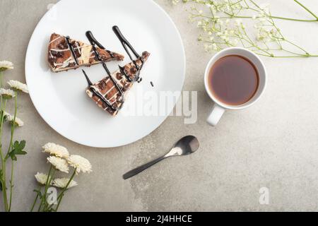 On the plate are two slices of cheesecake with tea and flowers, with space for congratulations Stock Photo