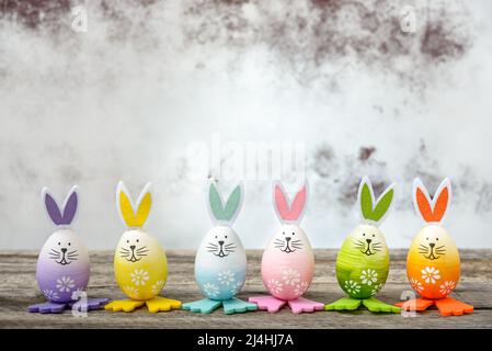 Group of Easter eggs with cute bunny face and rabbit ears on a rustic wooden table. Easter concept. Stock Photo