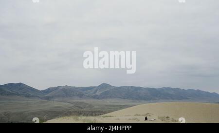 Beautiful desert mountains. Action. The desert against the white sky behind the big slightly green mountains and all in the sand. Stock Photo