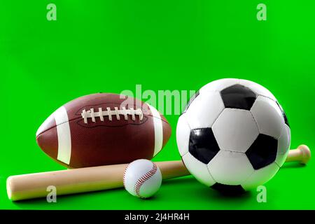 Sports equipment and leisure activity concept with a baseball bat and multiple balls used in different sports, like american football, baseball and so Stock Photo