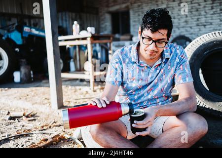 Young latin man serving mate and relaxing after work. Latin beverage. Stock Photo