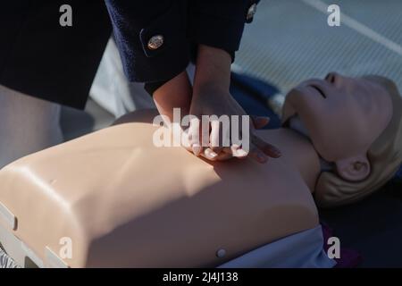 Details with the hands of a female student learning how to perform cardiopulmonary resuscitation (CPR) on a mannequin for educational purposes. Stock Photo