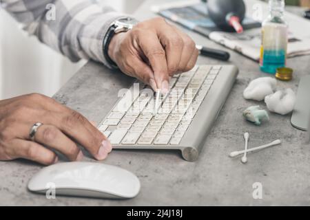 The man cleaning his computer keyboard. Grimy, more bacteria on keyboard. Stock Photo