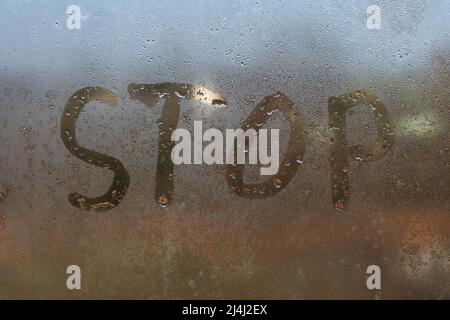 the word stop written on night wet window glass close-up with blurred background Stock Photo