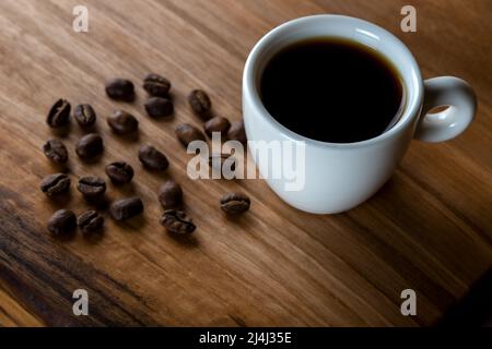 White cup of coffee with coffee beans on wooden background Stock Photo