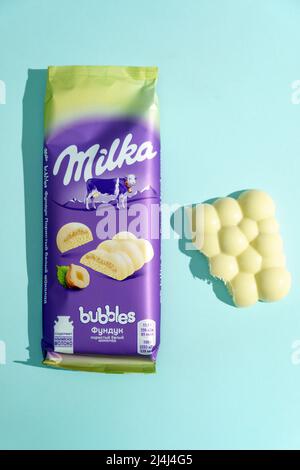 Tyumen, Russia-March 03, 2022: Milk white chocolate with hazelnuts milka. Blue background. Popular chocolate Stock Photo
