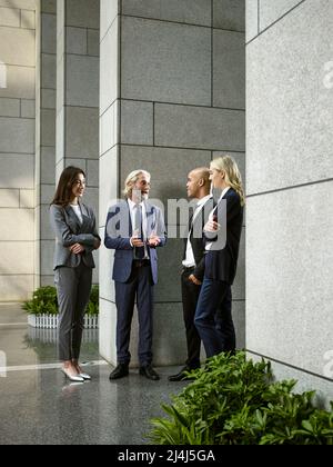 multinational and multiethnic business people standing talking chatting in lobby of modern office building. Stock Photo
