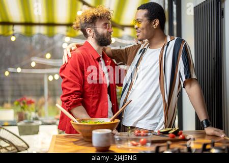 Two cool guys hugging while cooking at home Stock Photo