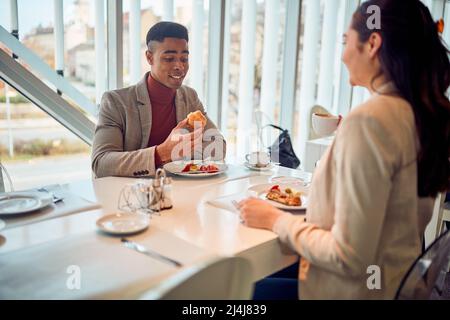 A young businessman is having a friendly talk with his young female colleague during a lunch break in a pleasant atmosphere in the canteen. Business, Stock Photo