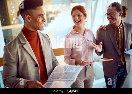 A young business woman is having a good time while chatting with her colleagues in a pleasant atmosphere in the hallway. Business, people, company Stock Photo