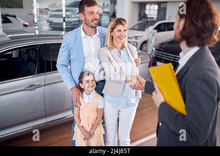 Saler congratulates young family on buying new car Stock Photo