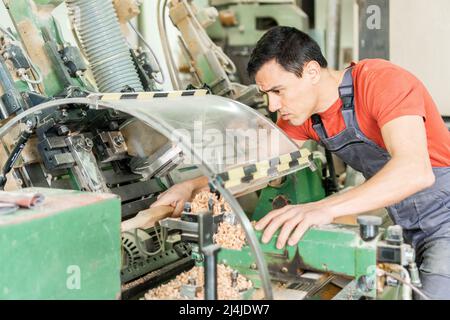 Handyman working with wood on turning machine in joinery Stock Photo