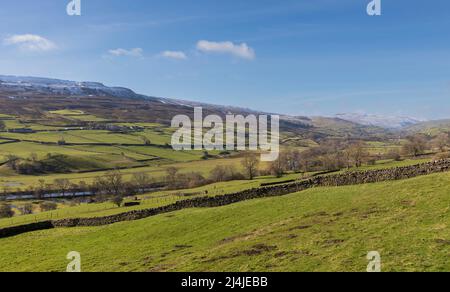 Swaledale, Yorkshire Dales National Park, Snow covered hills above a patchwork of dry stone wall lined fields and pastures with iconic stone barns.