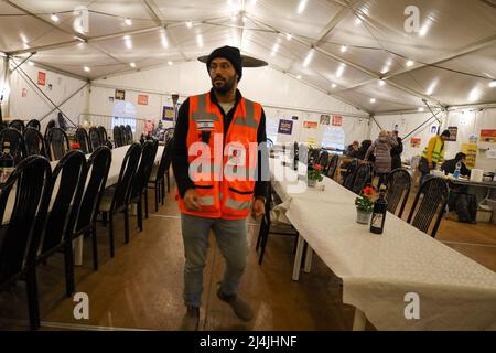 Medyka, Poland. 15th Apr, 2022. An Israeli volunteer at Medyka Border camp prepares the seder tables. Many Israelis and Ukrainian volunteers, along with Chinese, Scottish, Polish and others, celebrate a very special Passover at the Medyka Ukrainian Refugee Border Camp, an emergent humanitarian hub on the Polish side of the border between Poland and Ukraine, not far from Lviv. It was hosted by the Chinese volunteers in the 'New Federal State of China'' tent, and run by the Lev Echad, ('One Heart'' in English) staff and volunteers from Israel and elsewhere. Passover is a holiday celebrat Stock Photo