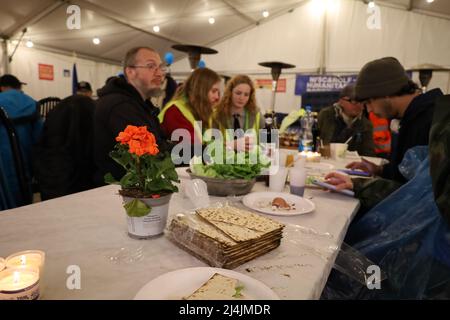 Medyka, Poland. 15th Apr, 2022. An international group of Jews from Israel and Ukraine, along with Chinese, Scottish, Polish and others, celebrate a very special Passover Seder at the Medyka Ukrainian Refugee Border Camp, an emergent humanitarian hub on the Polish side of the border between Poland and Ukraine, not far from Lviv. It was hosted by the Chinese volunteers in the 'New Federal State of China'' tent, and run by the Lev Echad, ('One Heart'' in English) staff and volunteers from Israel and elsewhere. Passover is a holiday celebrating the passing over from slavery and oppression i Stock Photo