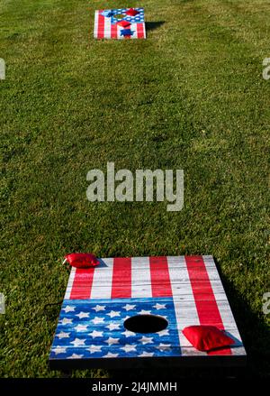 Cornhole boards painted as American flags on a thick green lawn ready for independence day parties. Stock Photo