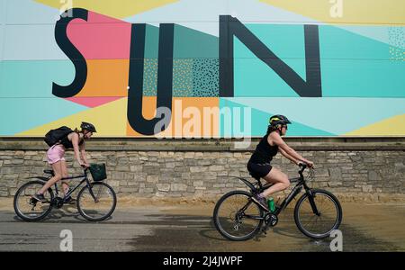 People cycle along the sea front on Boscombe beach as the UK is set for another day of warm weather ahead of Easter Sunday, after experiencing the hottest day of the year so far. Picture date: Saturday April 16, 2022. Stock Photo