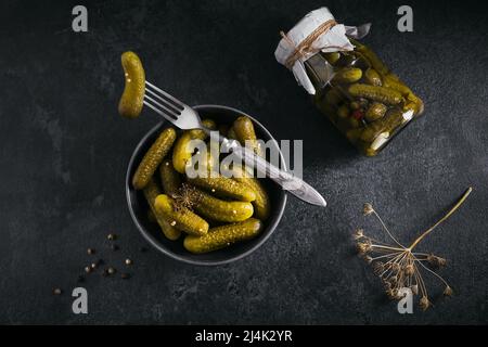 Homemade canning. Marinated cucumbers gherkins with dill and garlic in glass jar on black background Stock Photo