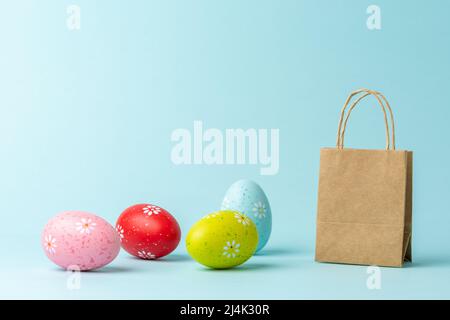 Different Easter eggs with shopping bag on blue background. Creative minimal shopping concept. Stock Photo