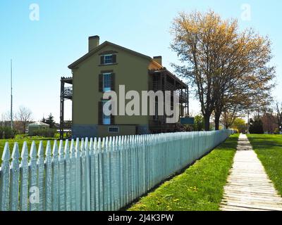 Sackets Harbor, New York, USA. April 2022. Sidewalk and picket fence leading past Fort Tompkins on Navy Point at Sackets Harbor. Stock Photo