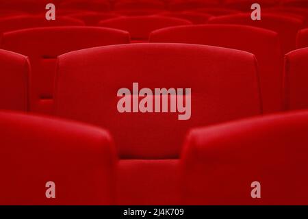 Rows of red velvet seats in a dark and totally empty. Stock Photo