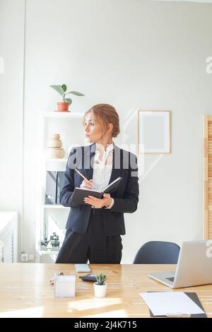 Successful smart businesswoman using laptop while doing some paperwork at the office Stock Photo