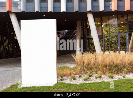 White blank outdoor billboard with copy space to add multiple company names and logos with modern business center building in background Stock Photo