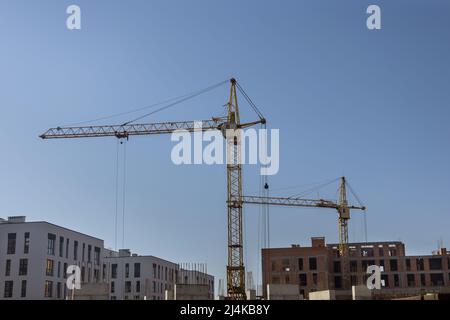 Two tower cranes near building with concrete building under construction Stock Photo