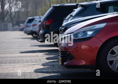 Many cars parked next to each other in a row in a parking lot. Focus on the red car in front Stock Photo