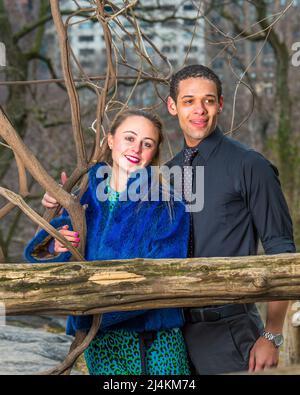 A young couple is standing outside in winter, smilingly looking forward. Stock Photo