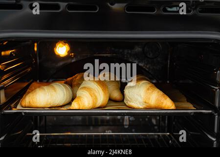 Croissant On Baking Sheet In Stainless Steel Oven Stock Photo