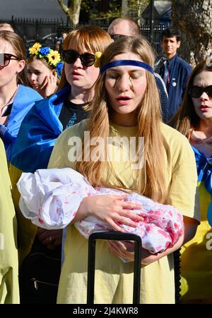 London, UK. 16th Apr 2022. A young woman holds a 'baby' covered in fake blood to illustrate the horrors of the conflict. Members of the Ukrainain Community attended a rally opposite Downing Street to request more support for Ukraine from the UK as the war with Russia continues. Credit: michael melia/Alamy Live News Stock Photo