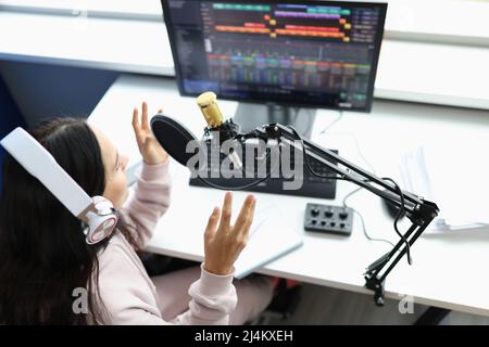 Woman in headphones in front of microphone broadcasts radio Stock Photo